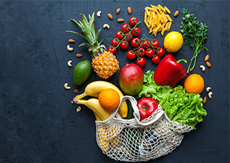 bag of colourful fruit and vegetables spilled out on a black background.