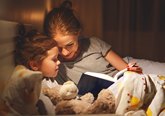 A mother reading a book to her child in bed