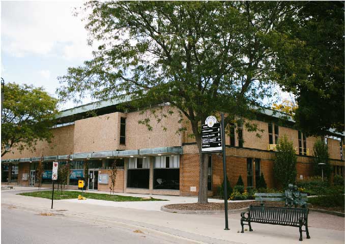 Red brick building with bench infront. 